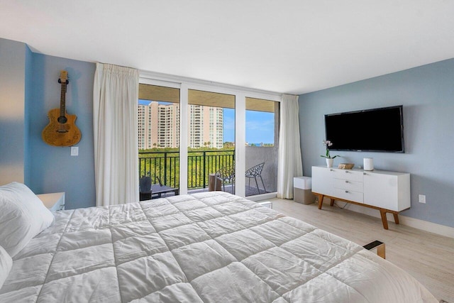 bedroom with baseboards, floor to ceiling windows, access to outside, and wood finished floors