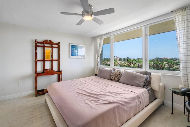 bedroom featuring light wood finished floors, baseboards, and ceiling fan