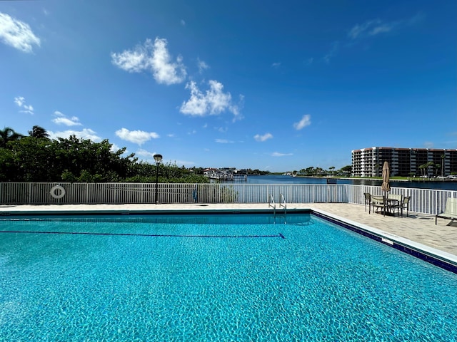 pool with a water view, fence, and a patio