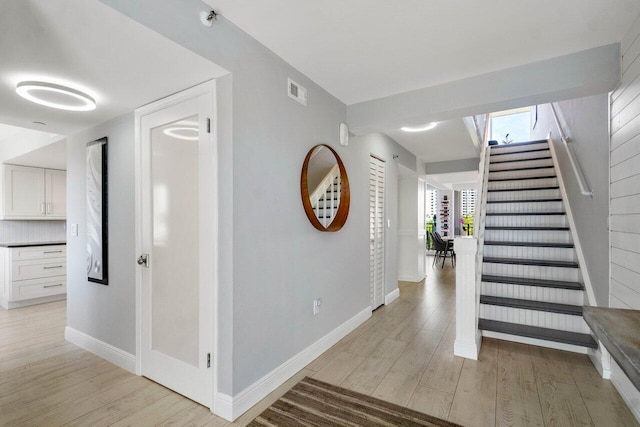 interior space featuring baseboards, stairs, visible vents, and light wood-type flooring