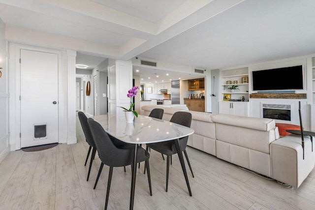 dining area featuring a fireplace, visible vents, and light wood-style floors