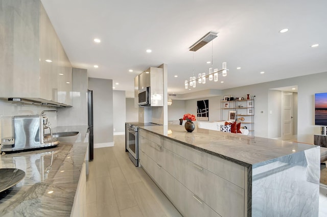 kitchen with light stone counters, stainless steel appliances, sink, pendant lighting, and light hardwood / wood-style flooring