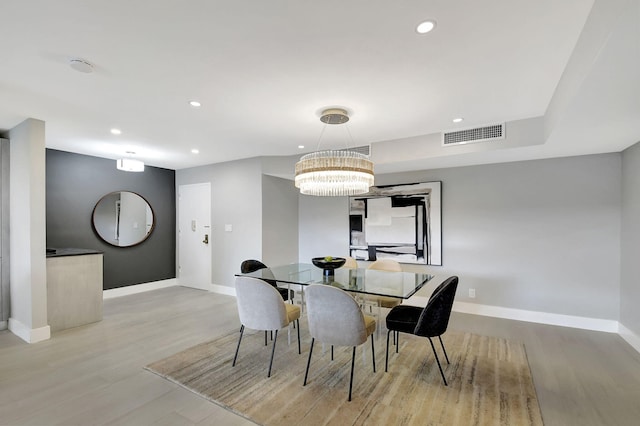 dining space with light hardwood / wood-style flooring and a chandelier