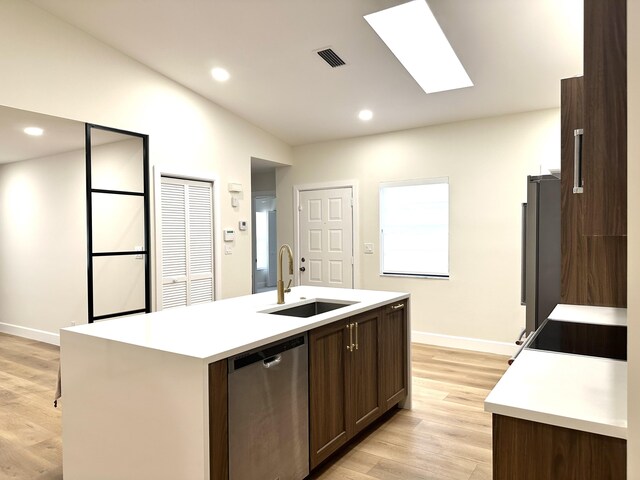 kitchen with light hardwood / wood-style flooring, backsplash, appliances with stainless steel finishes, a kitchen island with sink, and sink