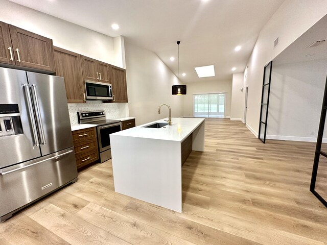 kitchen with a kitchen island with sink, dark brown cabinets, and sink