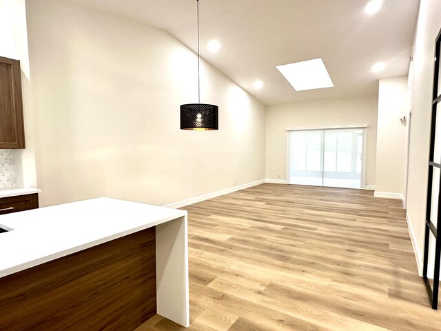 kitchen with decorative light fixtures, stainless steel refrigerator with ice dispenser, a center island with sink, sink, and light wood-type flooring