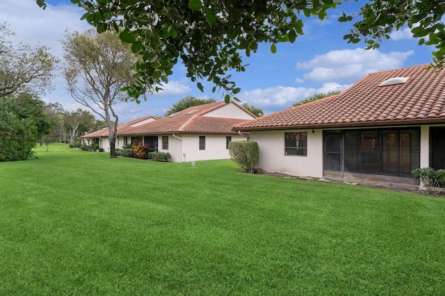 back of house with a sunroom and a lawn