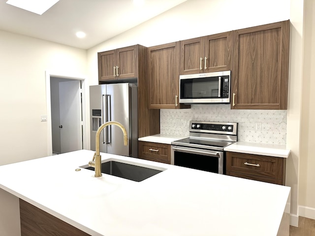 kitchen featuring backsplash, vaulted ceiling, hardwood / wood-style floors, stainless steel appliances, and sink