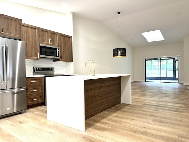 kitchen with light countertops, appliances with stainless steel finishes, light wood-type flooring, and pendant lighting