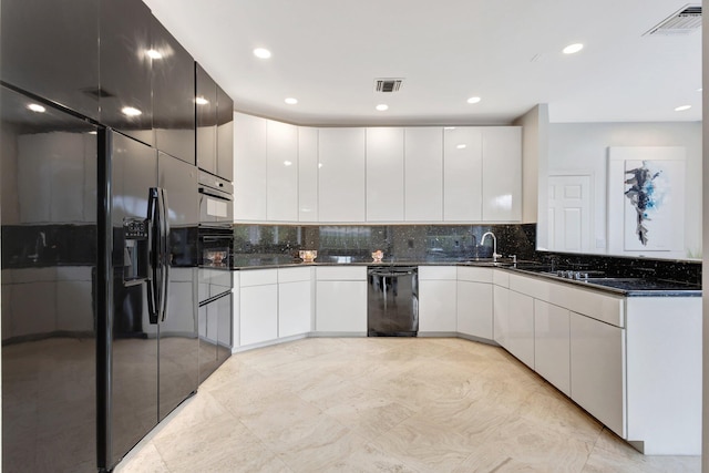 kitchen featuring dark stone countertops, white cabinetry, dishwasher, and light tile patterned floors