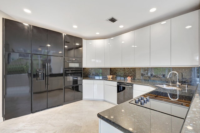 kitchen featuring sink, dark stone counters, white cabinetry, and backsplash