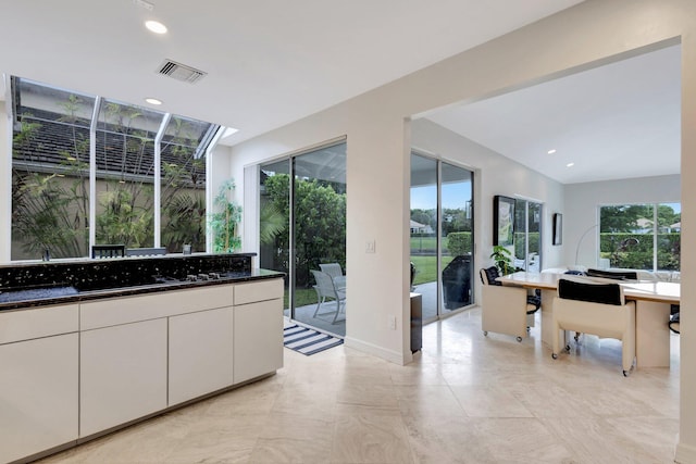 kitchen with light tile patterned floors, dark stone countertops, and plenty of natural light