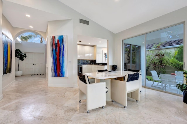 tiled dining room featuring sink and lofted ceiling