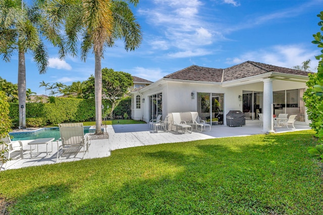 back of property featuring a patio, a lawn, and a fenced in pool