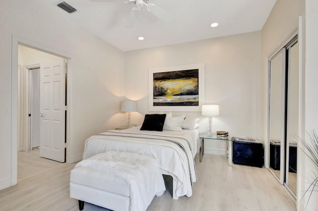 bedroom with light hardwood / wood-style flooring, ceiling fan, and a closet