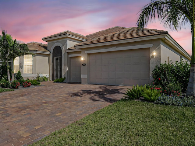 mediterranean / spanish-style house with a garage and a yard