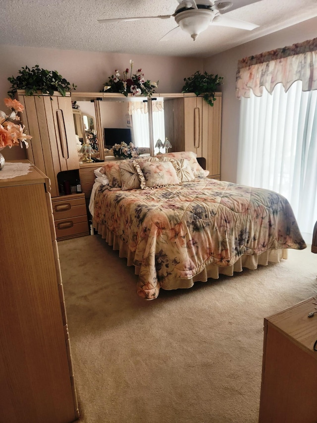 carpeted bedroom featuring ceiling fan and a textured ceiling