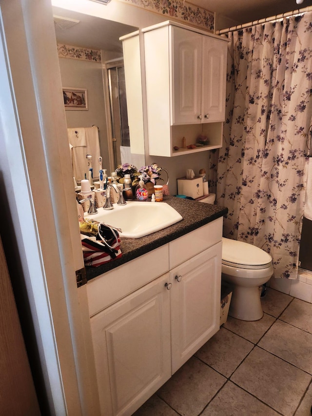 bathroom with toilet, vanity, and tile patterned floors