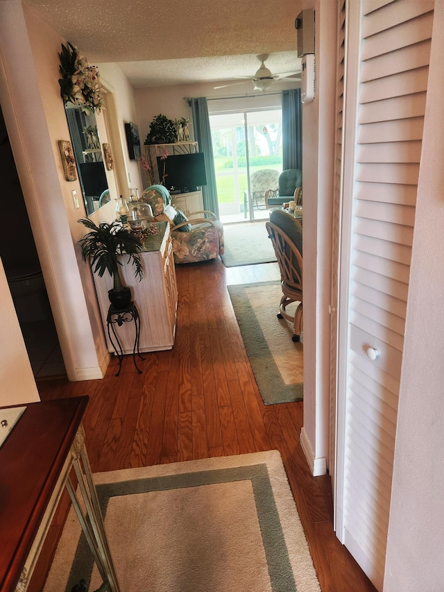 hallway with dark wood-type flooring and a textured ceiling