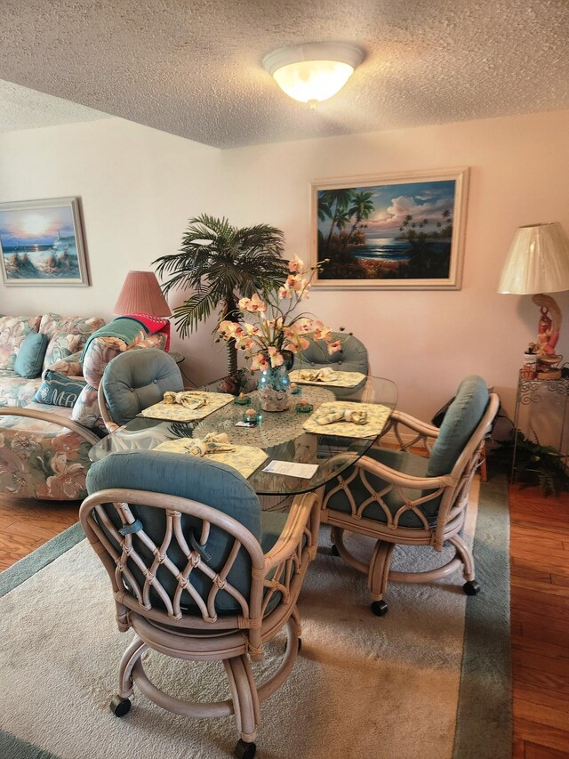 dining space with a textured ceiling and hardwood / wood-style floors