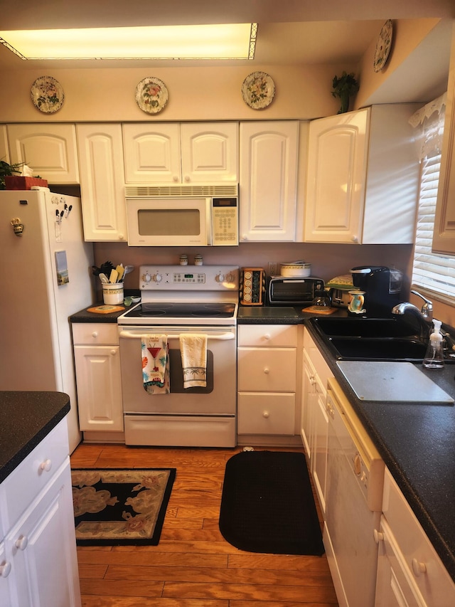 kitchen featuring sink, white appliances, light hardwood / wood-style floors, and white cabinetry