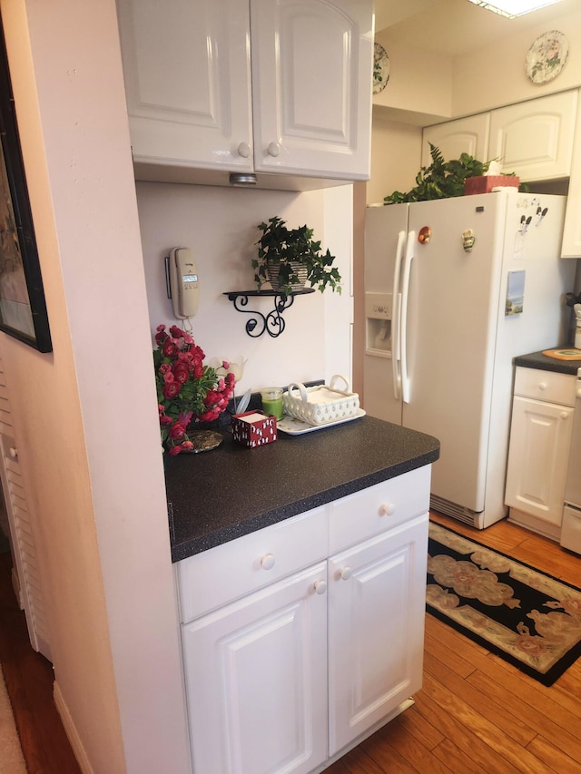 kitchen with white cabinets, light hardwood / wood-style flooring, and white refrigerator with ice dispenser