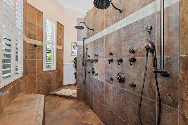 bathroom featuring crown molding, tile patterned flooring, a tile shower, and tile walls