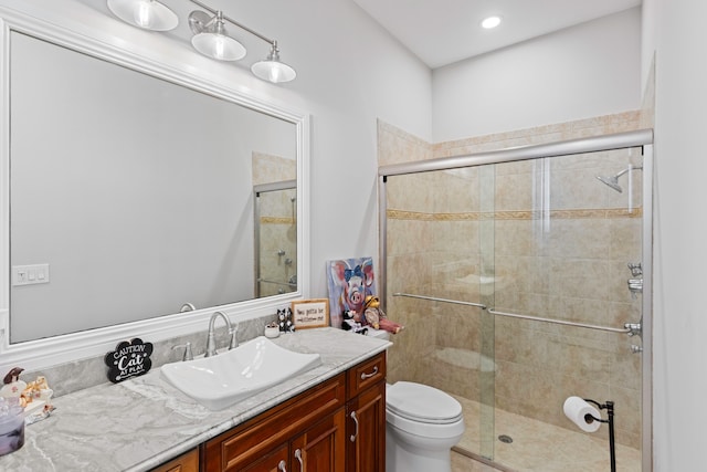 bathroom featuring a shower with door, toilet, and vanity