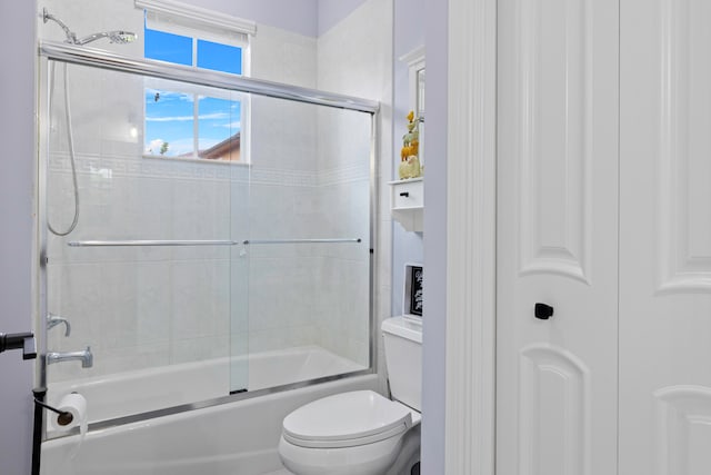 bathroom with toilet and combined bath / shower with glass door