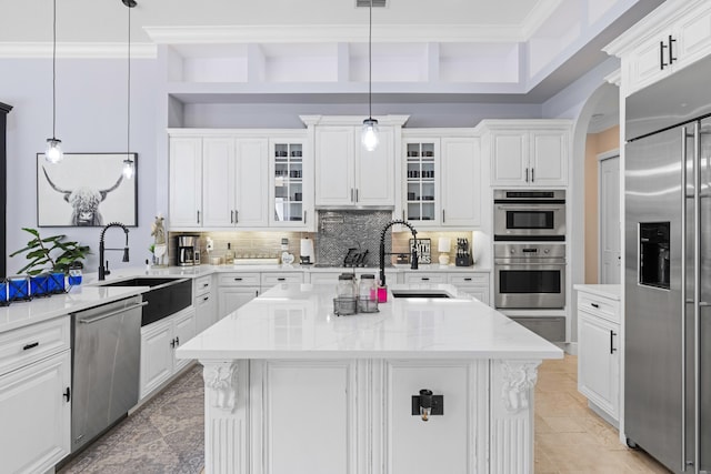 kitchen featuring stainless steel appliances, ornamental molding, a center island with sink, and white cabinets