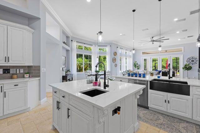 kitchen with ornamental molding, white cabinets, dishwasher, sink, and a center island with sink