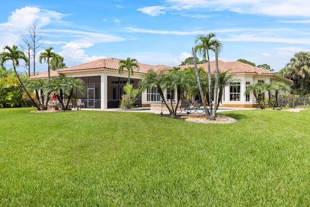 rear view of house featuring a pool, a sunroom, and a yard