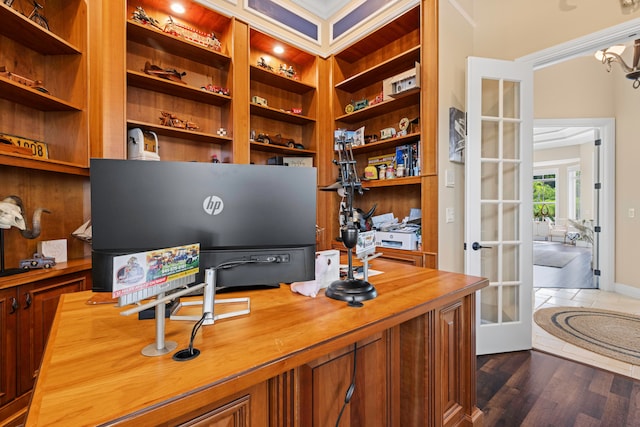 office space with crown molding, french doors, dark hardwood / wood-style flooring, and built in shelves