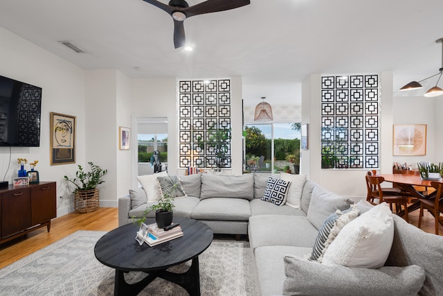 living room with light hardwood / wood-style floors, a healthy amount of sunlight, and ceiling fan