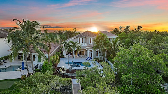 mediterranean / spanish house featuring a tile roof, a patio area, a balcony, a fenced backyard, and an outdoor pool