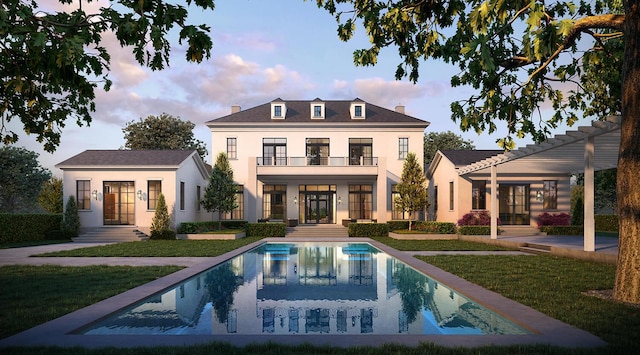 back of house at dusk with french doors, stucco siding, a lawn, a balcony, and an outdoor pool