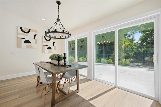 dining area with vaulted ceiling, hardwood / wood-style floors, and a chandelier