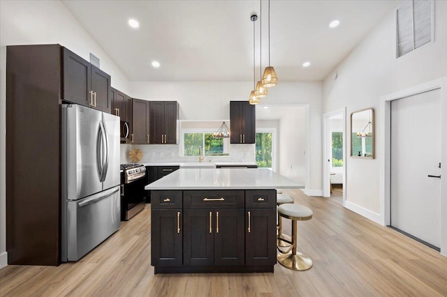 kitchen with light hardwood / wood-style flooring, backsplash, appliances with stainless steel finishes, and a kitchen island