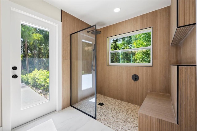 bathroom with tiled shower and wood walls