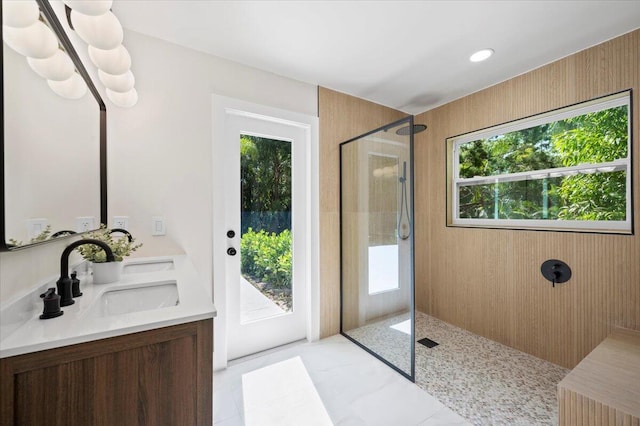 bathroom with vanity, a tile shower, a healthy amount of sunlight, and wooden walls