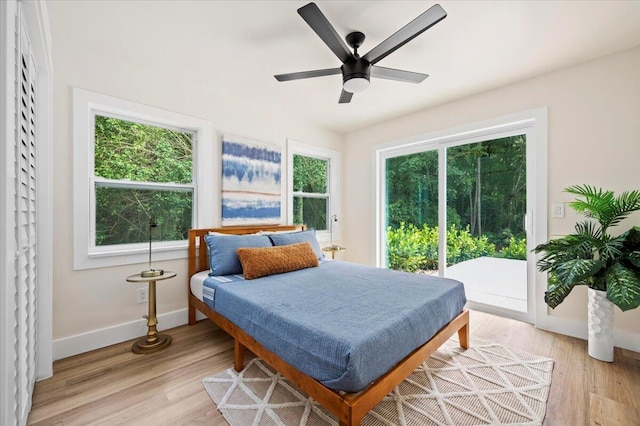 bedroom featuring light wood-type flooring, multiple windows, access to exterior, and ceiling fan