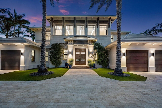 italianate home featuring a standing seam roof, french doors, an attached garage, and decorative driveway