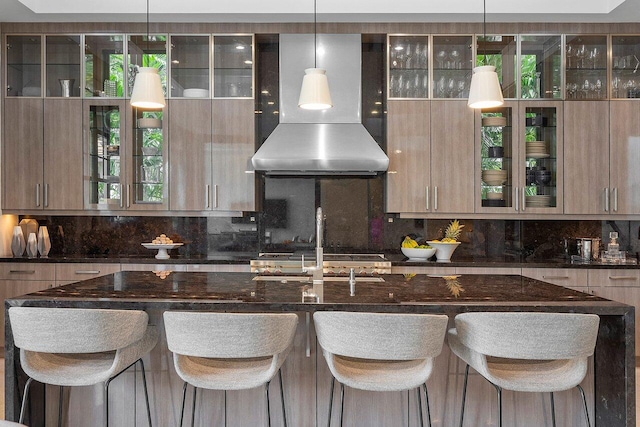 kitchen featuring decorative light fixtures, modern cabinets, ventilation hood, and a kitchen breakfast bar