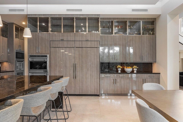 kitchen with hanging light fixtures, dark countertops, visible vents, and modern cabinets