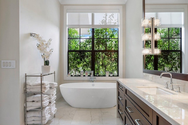 bathroom featuring vanity, marble finish floor, and a freestanding bath