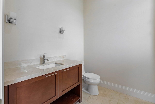 half bath with vanity, toilet, and baseboards