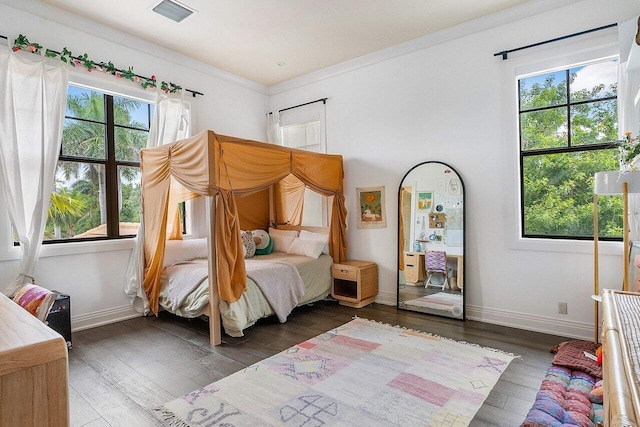 bedroom with dark wood finished floors, baseboards, ornamental molding, and visible vents