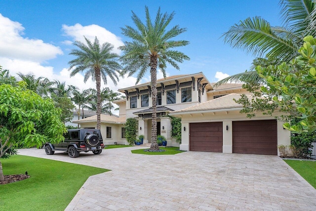 italianate home with a front lawn, stucco siding, decorative driveway, and a garage