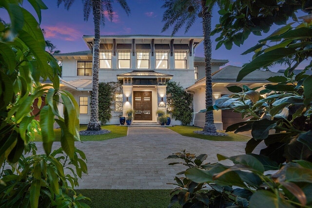 view of front of house featuring stucco siding, french doors, and decorative driveway