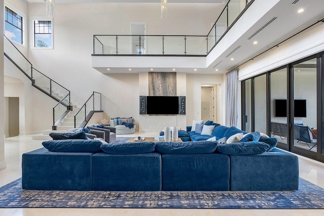 living area featuring visible vents, recessed lighting, stairway, and a high ceiling